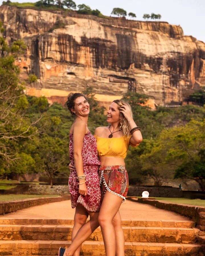 travelers standing near the base gardens with the towering rock cliffs in the background