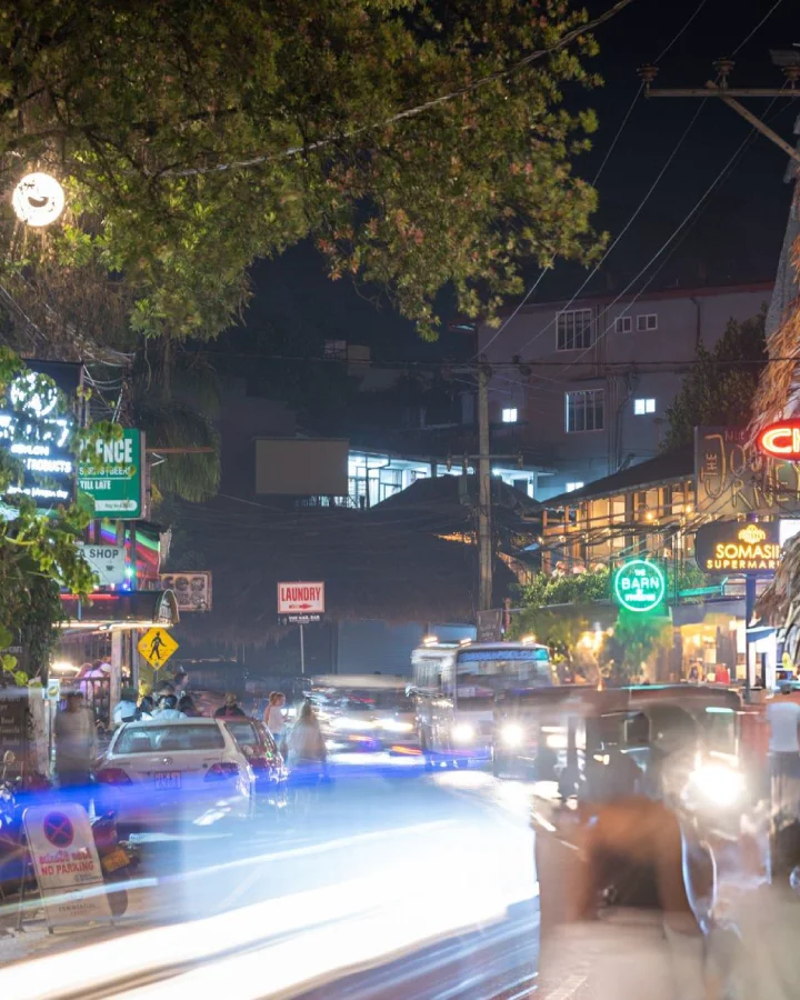 Busy street in Ella, Sri Lanka at night with shops, traffic, and blurred lights from passing vehicles