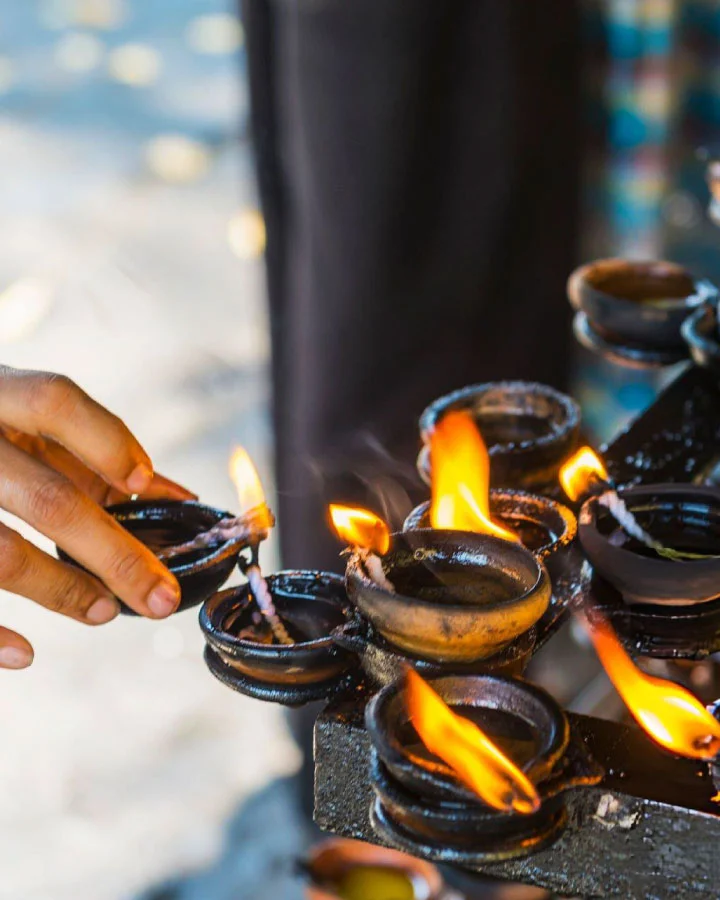 Lighting traditional oil lamps during Buddhist worship in temple of tooth relic kandy