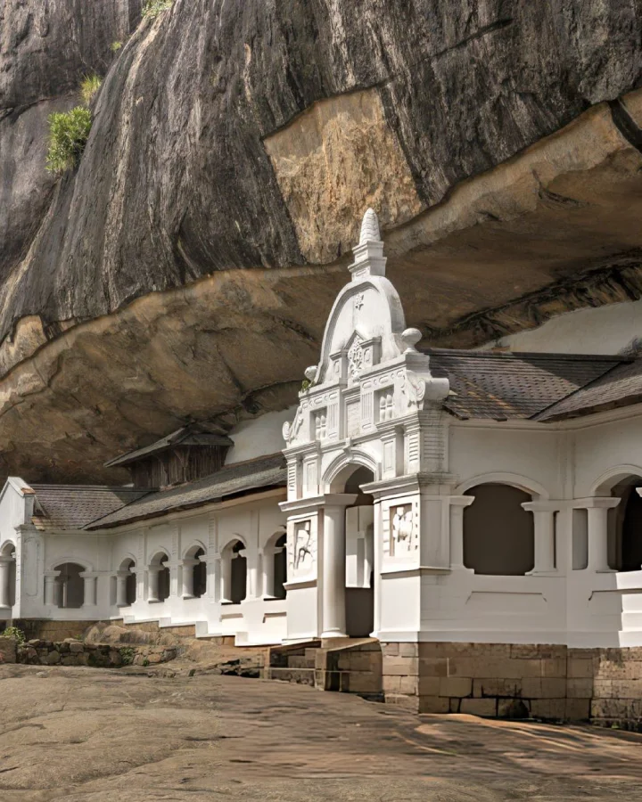 White cave shrine built beneath rock formations at the Dambulla Cave Temple complex