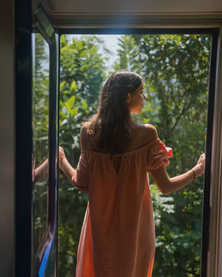Young woman standing at an open train door while traveling to ella