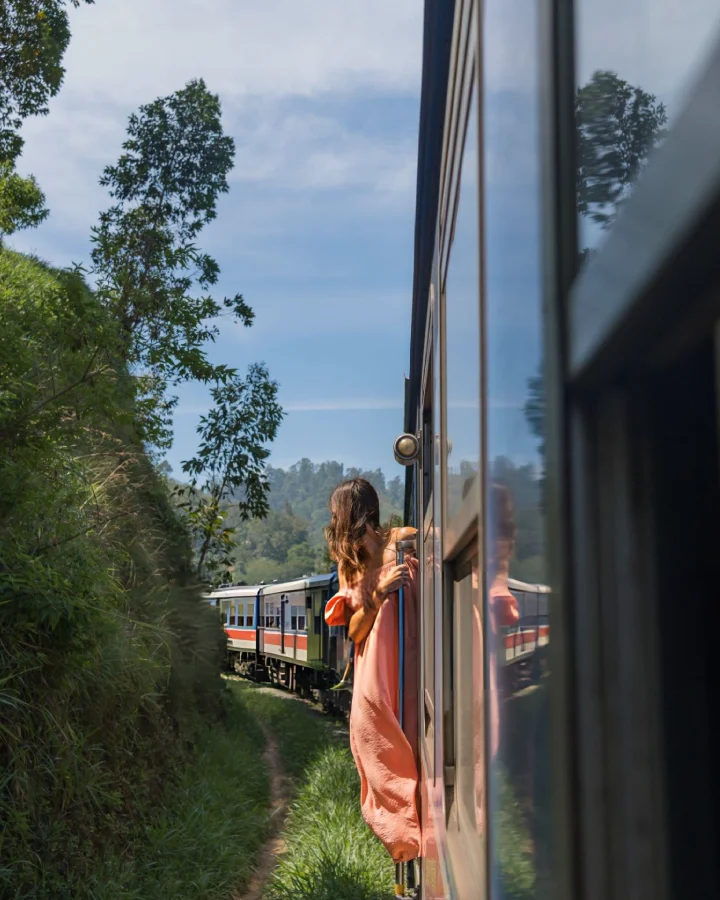 woman leaning out of a train door on the way to ella